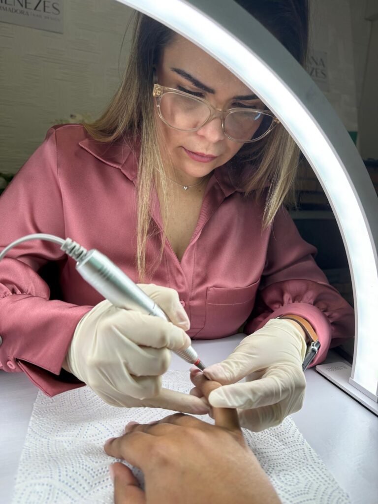 Profissional a trabalhar uma unha com broca, sob uma luz circular