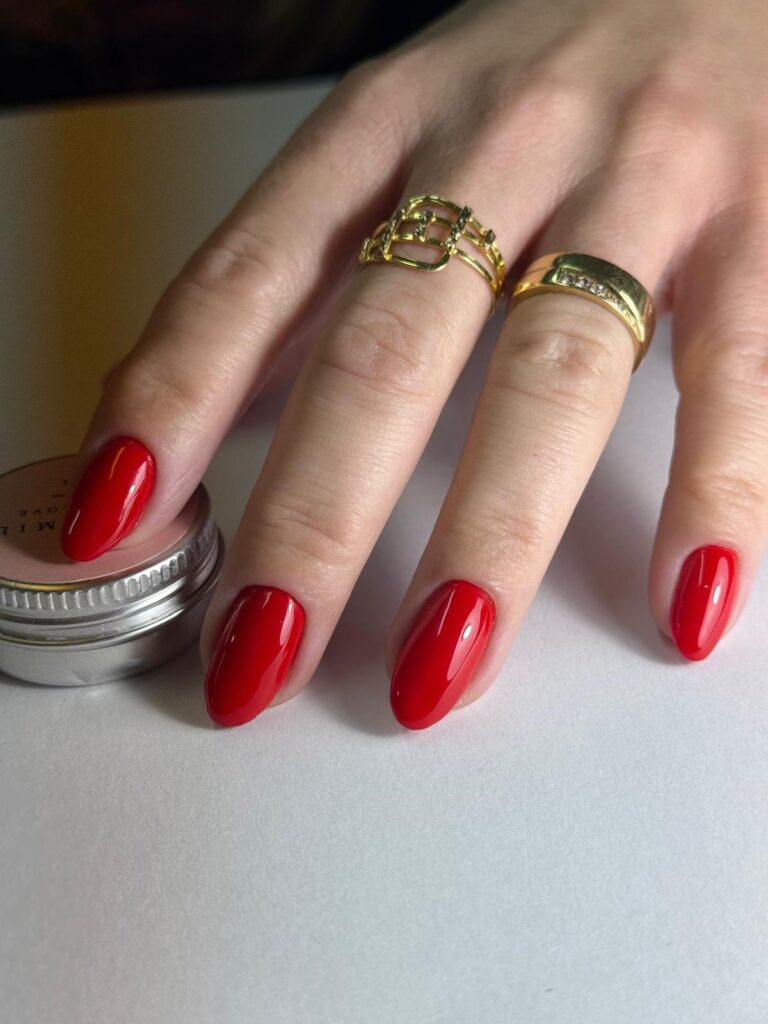 Unhas vermelhas em amêndoa curta, com anéis dourados
