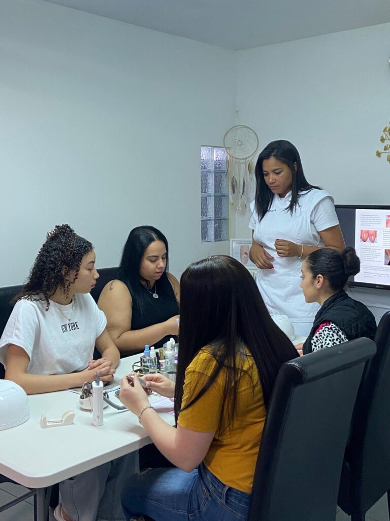 Formadora de branco a acompanhar as alunas à mesa de trabalho