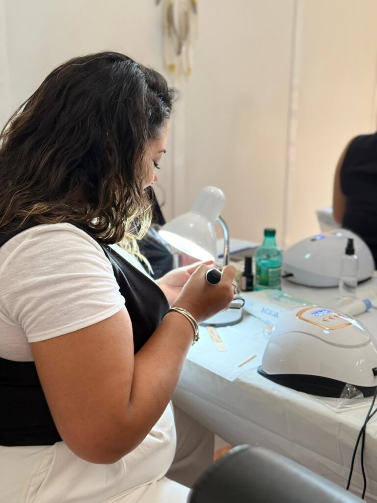 Aluna a trabalhar uma unha ao lado da lâmpada LED
