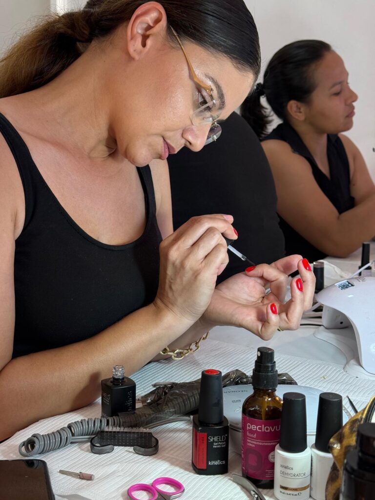 Aluna a pintar uma unha, com produtos profissionais na mesa