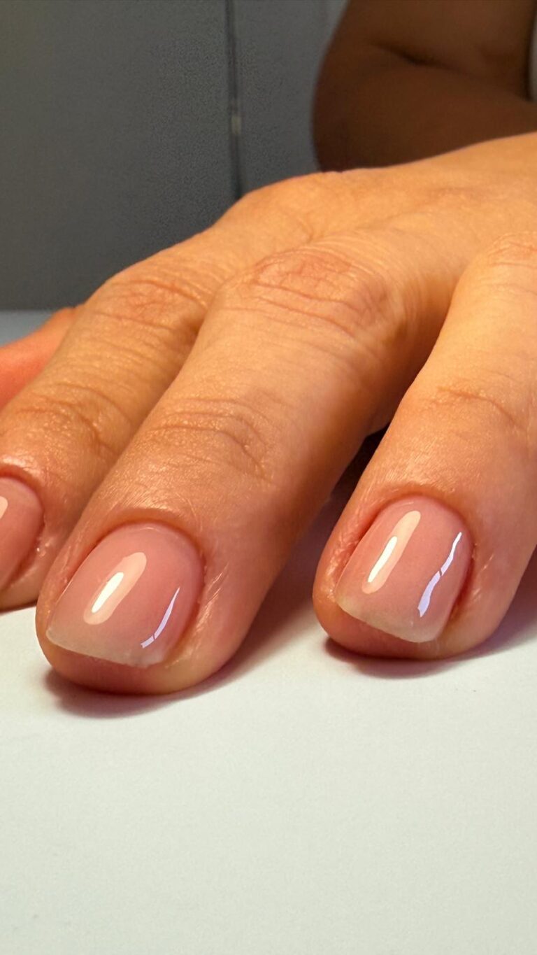 Mão com unhas curtas e brilhantes de tom nude