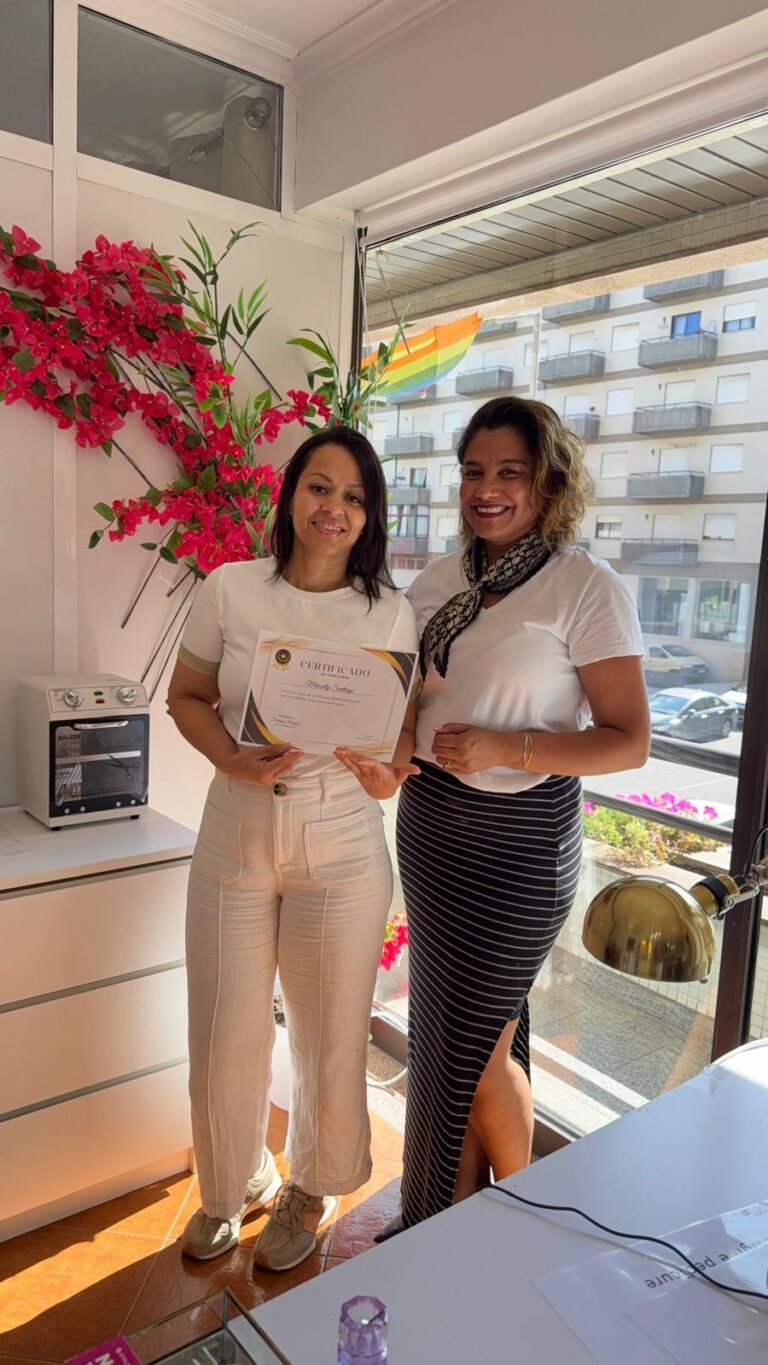 Duas mulheres com um certificado, junto à janela com flores
