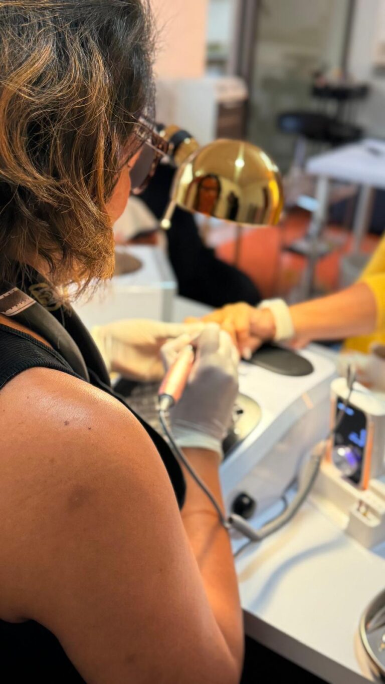 Profissional a trabalhar numa mesa de manicure, com candeeiro dourado