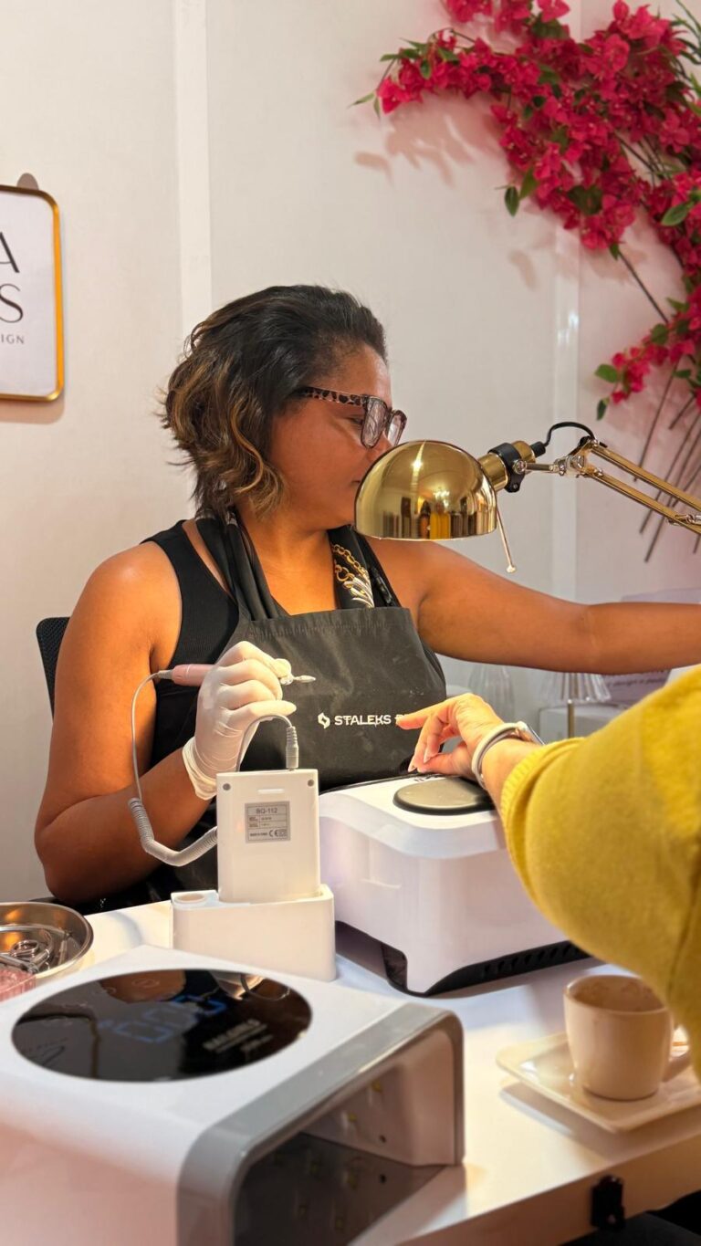 Profissional a fazer uma manicure num espaço luminoso com flores cor-de-rosa